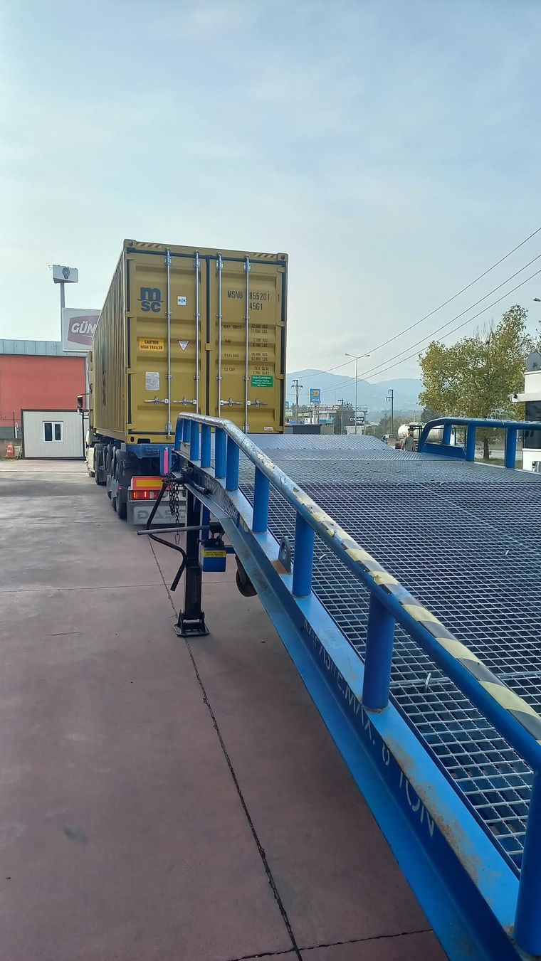 Tıra yüklü konteyner ve yanında konumlandırılmış mavi mobil rampa