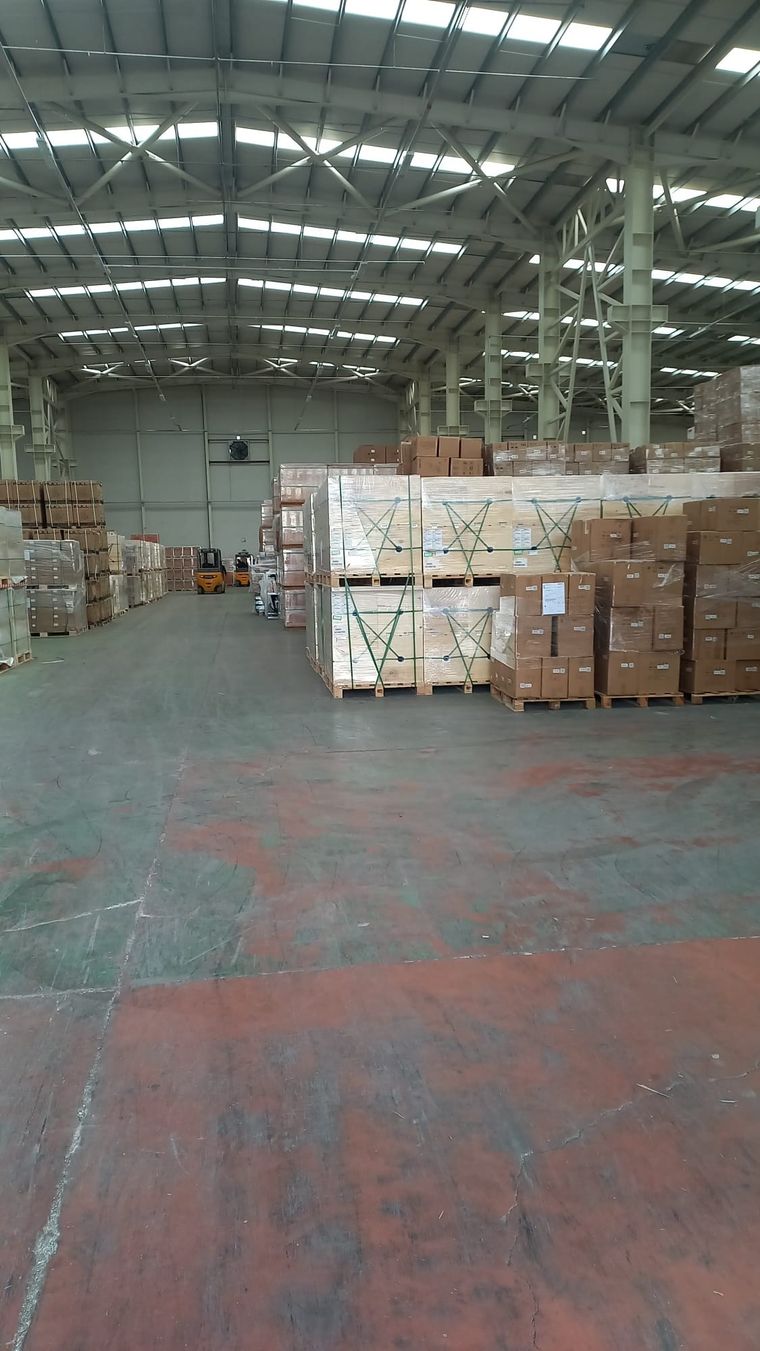 Depo içinde paletlenmiş ve streçlenmiş yük istifleri, uzakta forklift